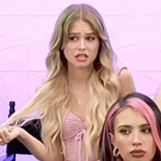 a woman with blonde hair is making a funny face while standing next to a woman with pink hair .