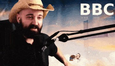 a man wearing a cowboy hat is talking into a microphone in front of a poster for bbc