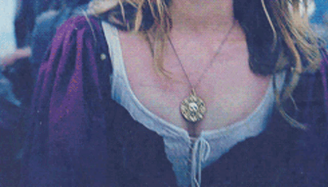a woman is wearing a necklace with a skull pendant