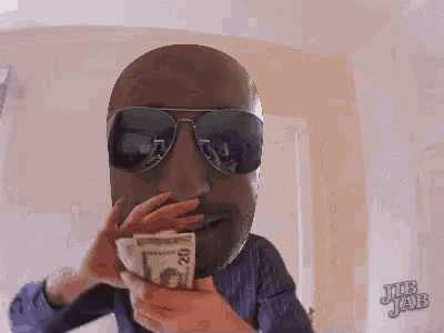 a man wearing sunglasses is holding twenty dollar bills