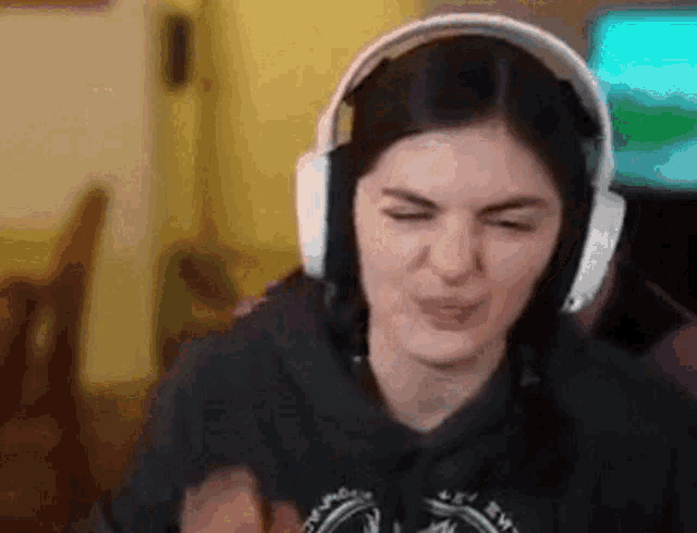 a woman wearing headphones is making a funny face while sitting in front of a computer screen .