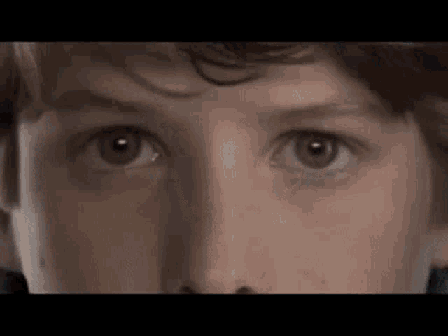 a close up of a young boy 's eyes with a black background .