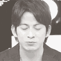 a man in a suit is making a funny face with his eyes closed .