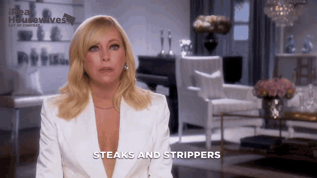a woman in a white suit says steaks and strippers in a living room