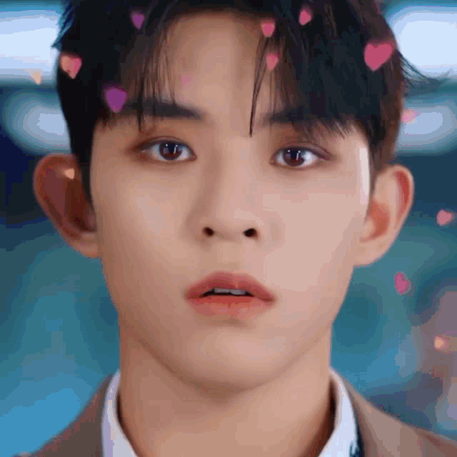 a close up of a young man 's face with hearts falling from his hair