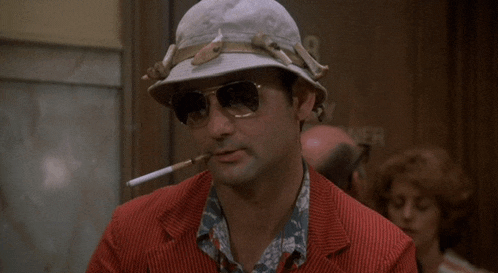 a man in a hat and sunglasses is smoking a cigarette
