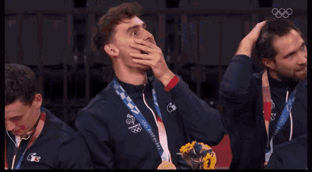 a man wearing a medal that says tokyo 2020 is laughing