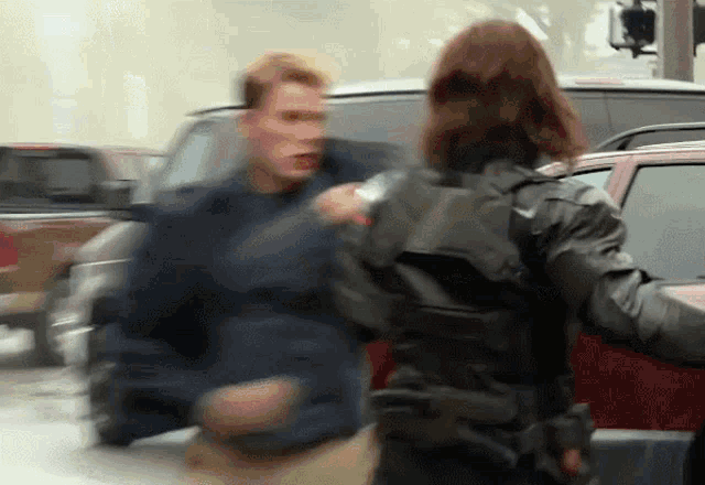 a man in a blue jacket is being held by a woman in a black vest