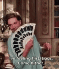 a woman is holding a fan in her hand and says `` i 'm feeling flirtatious . come hither . ''