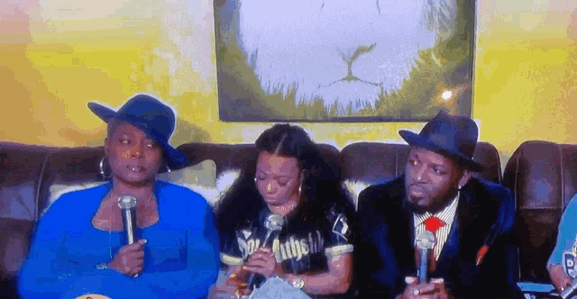 a group of people sitting on a couch with microphones in their hands