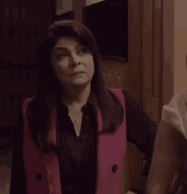 a woman wearing a pink vest and a black shirt is holding a person 's arm .
