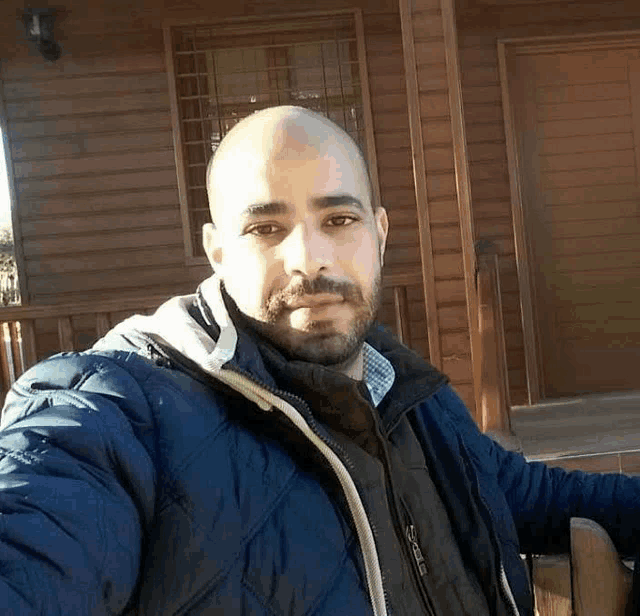 a man is taking a selfie in front of a wooden house .