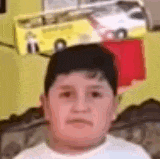 a young boy is sitting on a couch in front of a toy car .