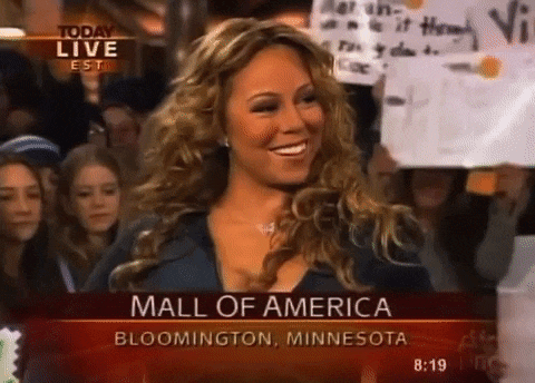 a woman is smiling in front of a crowd at the mall of america in minnesota