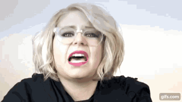 a woman wearing glasses is making a funny face with her mouth open .