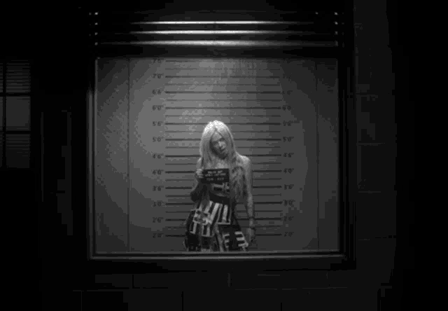 a black and white photo of a woman standing in front of a wall with measurements
