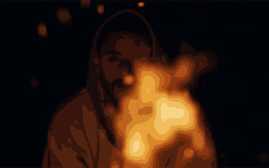 a man standing in front of a fire with a hood on