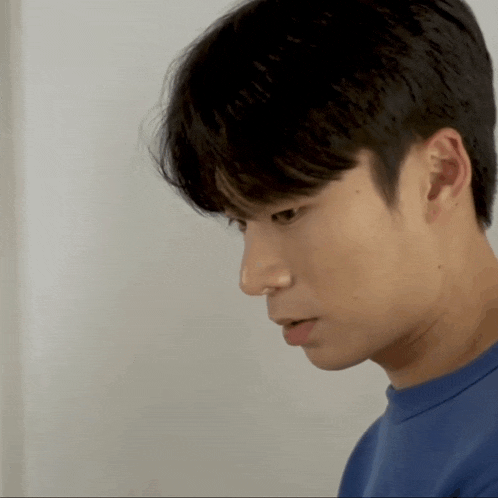 a close up of a young man 's face in a blue shirt