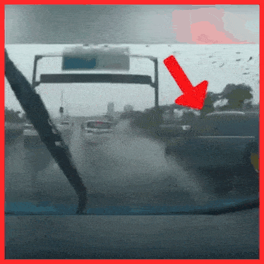 a car windshield with a red arrow pointing to a sign above it