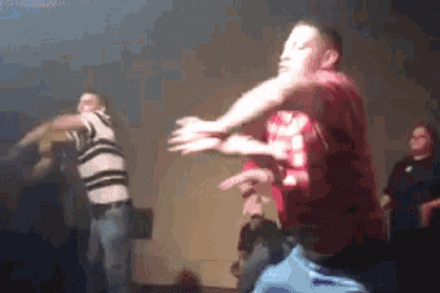 a man in a red shirt is dancing in a dark room with other people
