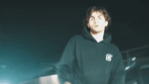a man in a black hoodie is dancing in the dark