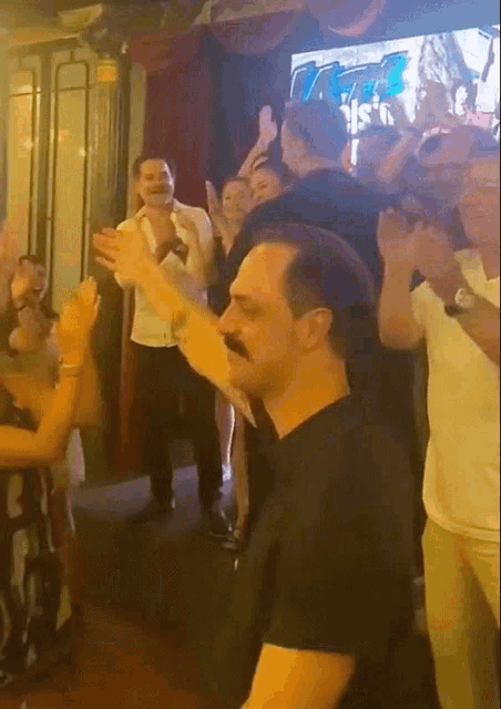 a man with a mustache is dancing in front of a crowd of people