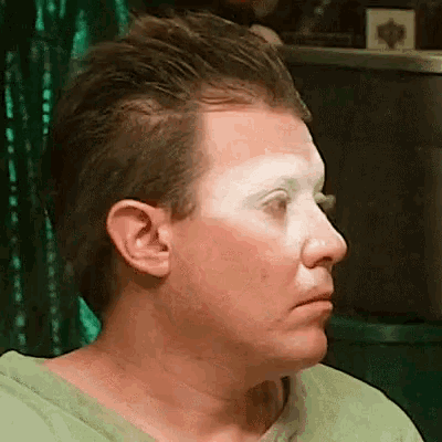 a close up of a man 's face with a green shirt on