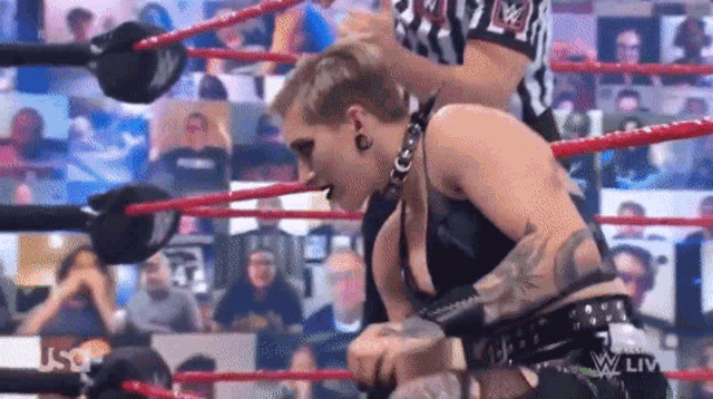a woman is wrestling in a wrestling ring while a referee looks on .