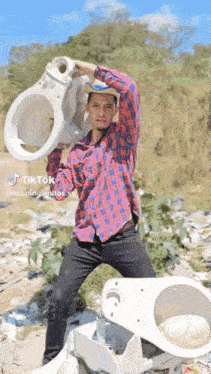 a man in a plaid shirt is holding a broken toilet