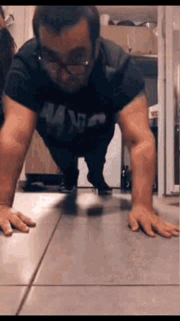 a man wearing glasses is doing push ups on a tile floor