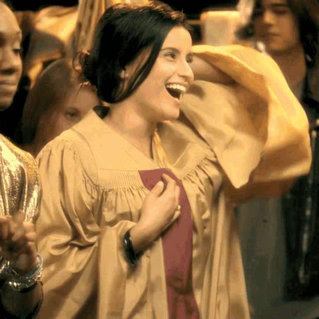 a woman in a graduation gown is smiling and holding a red scarf