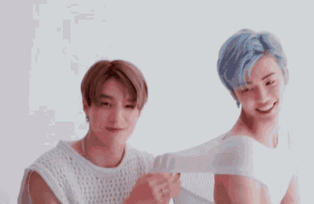 two young men are standing next to each other on a white background and smiling .