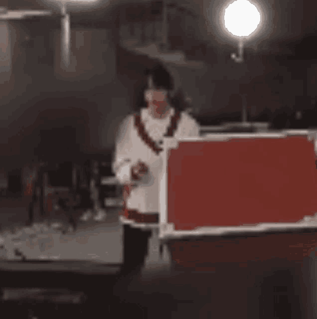 a person is standing in front of a red box in a room .