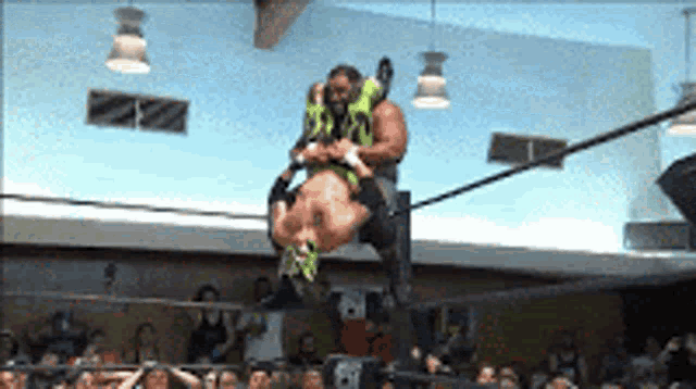 a wrestler is being lifted in the air by another wrestler wearing a green mask with the number 30 on it