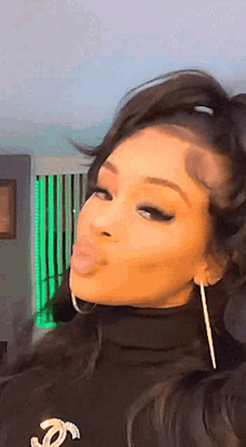 a woman wearing a turtleneck and earrings is blowing a kiss .