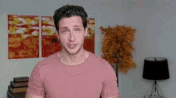 a man in a pink shirt stands in front of a lamp and a tree