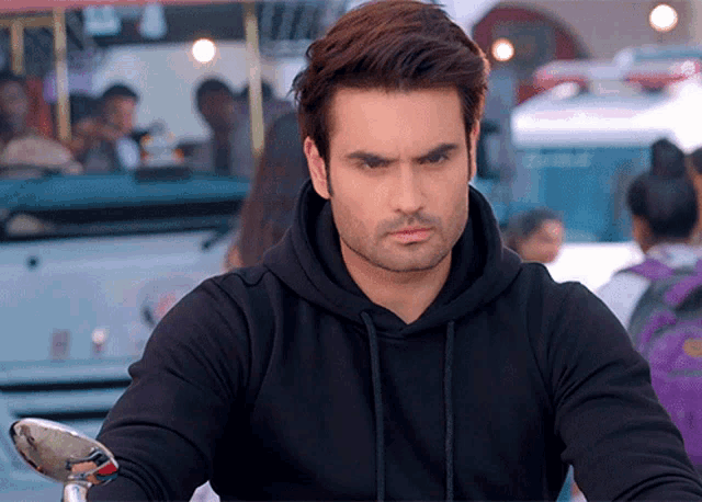 a man wearing a black hoodie is looking at the camera