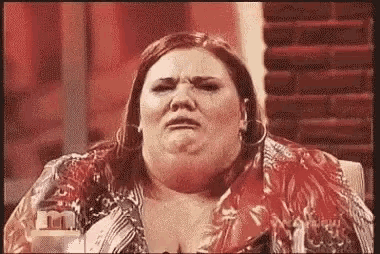 a very fat woman is sitting in a chair and making a sad face .