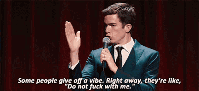 a man in a suit and tie is holding a microphone and saying some people give off a vibe
