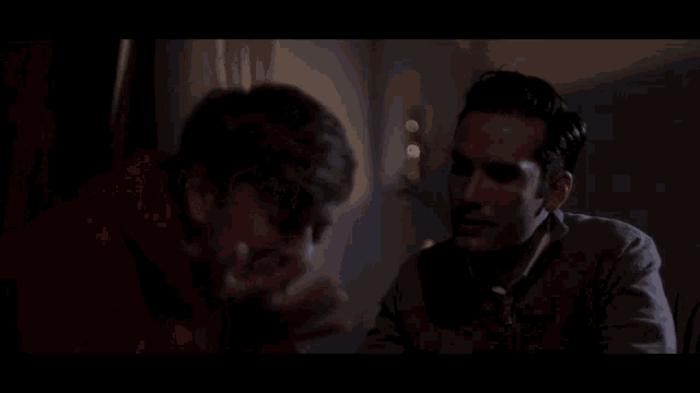 a man in a red hoodie talks to another man