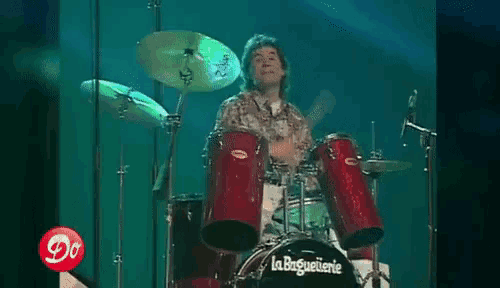 a man is playing drums in front of a la baguetterie drum set .