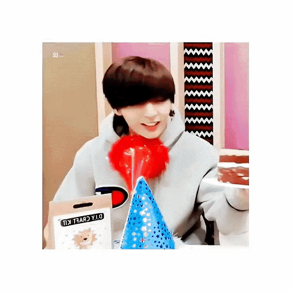 a boy wearing a party hat holds a cake