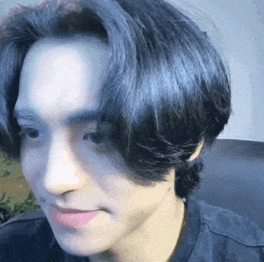 a close up of a man 's face with long black hair and a black shirt