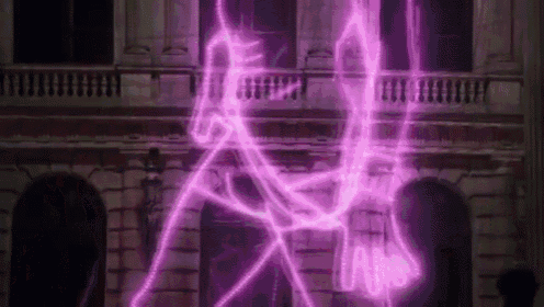 a purple light is coming out of a building and a person is standing in front of it .