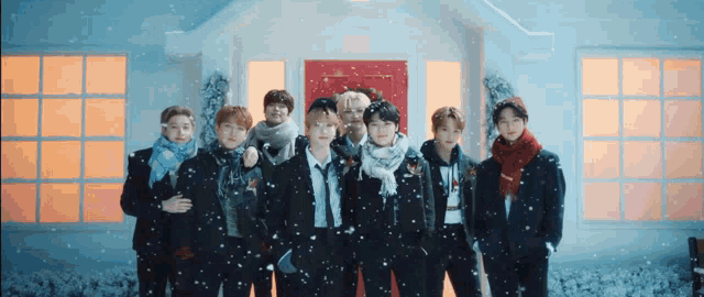 a group of young men standing in front of a house with snow falling