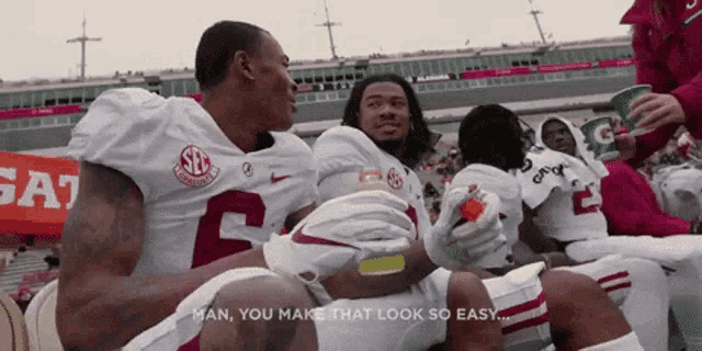 a group of alabama football players sitting on the sidelines