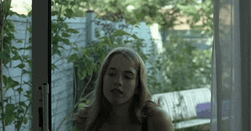 a woman in a black bra is sitting in front of a sliding glass door .