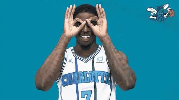 a man in a basketball jersey is making a funny face with his hands .