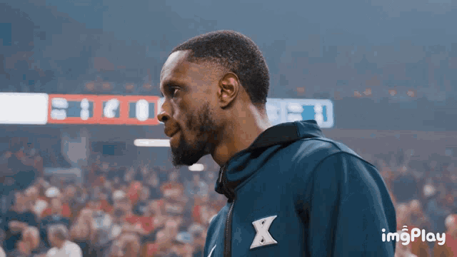a man in a blue jacket stands in front of a scoreboard that says 13 to 0
