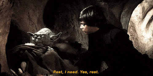 a man standing next to a statue of yoda says rest i need yes rest